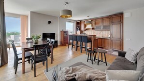 Un salon moderne comprenant un coin repas, une cuisine et une grande fenêtre donnant sur la ville.