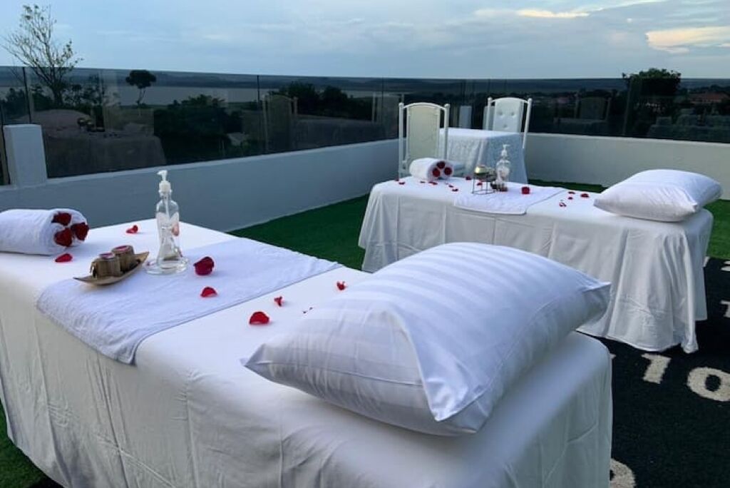 A rooftop terrace with two massage tables covered in white linens, each with a pillow and a bottle of lotion.