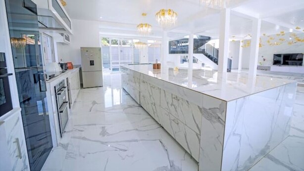 Una cocina moderna con encimeras de mármol, electrodomésticos de acero inoxidable y una isla central.