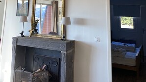 Een kamer met een aan de muur bevestigd hertshoofd, een open haard met een bovenplaat en een spiegel erboven.