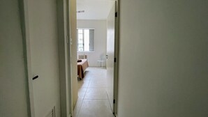 Un pasillo estrecho que conduce a una habitación con una cama y una silla.