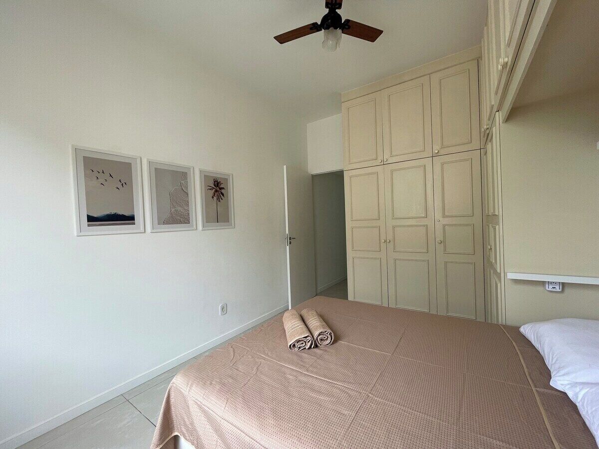 A bedroom with a bed, a ceiling fan, and a wardrobe.
