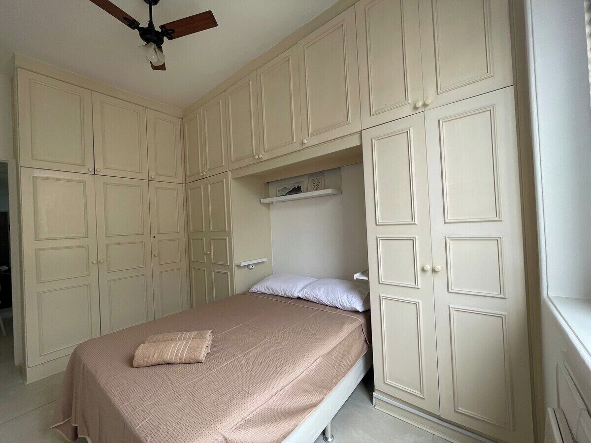 Une chambre à coucher avec un lit, un ventilateur de plafond et des placards intégrés.