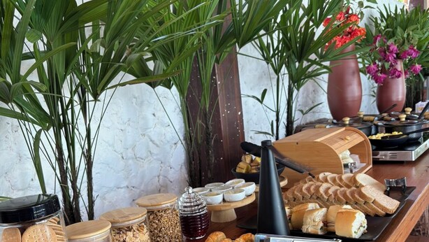Mesa de buffet com diversos alimentos, incluindo doces, pães e acompanhamentos.