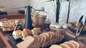 Una mesa de buffet con diferentes alimentos, como sándwiches, pan y salsas.