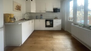 A compact kitchen with white cabinets, a built-in oven, a microwave, and a window providing a view of the outside. - Rudbecksgatan  (Eskilstuna)