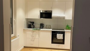 A modern kitchen with white cabinetry, a built-in oven, and a microwave. - Rudbecksgatan  (Eskilstuna)