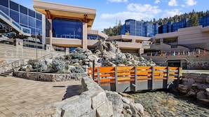 Un bâtiment moderne doté d’une façade en verre, d’un escalier en pierre et d’une petite cascade décorative.