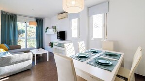 Un soggiorno moderno con un divano, un tavolo da pranzo per quattro persone e una televisione su un mobile bianco.