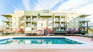 Un moderno edificio residenziale con una piscina di fronte.