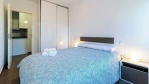 Una camera da letto con un letto, un comodino, un armadio e una piccola cucina.