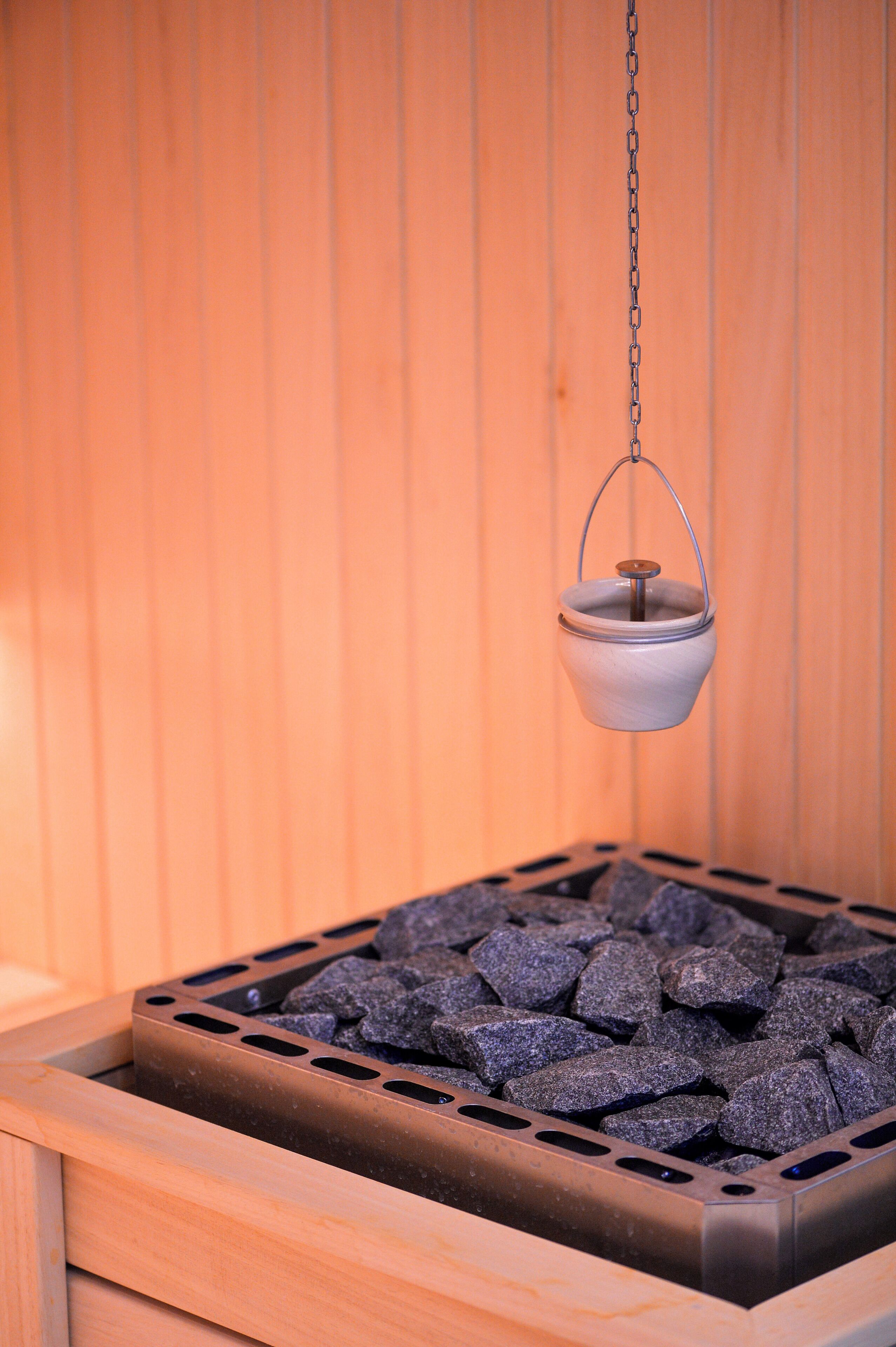 Un sauna équipé d’un récipient métallique suspendu et d’un plateau rempli de pierres.