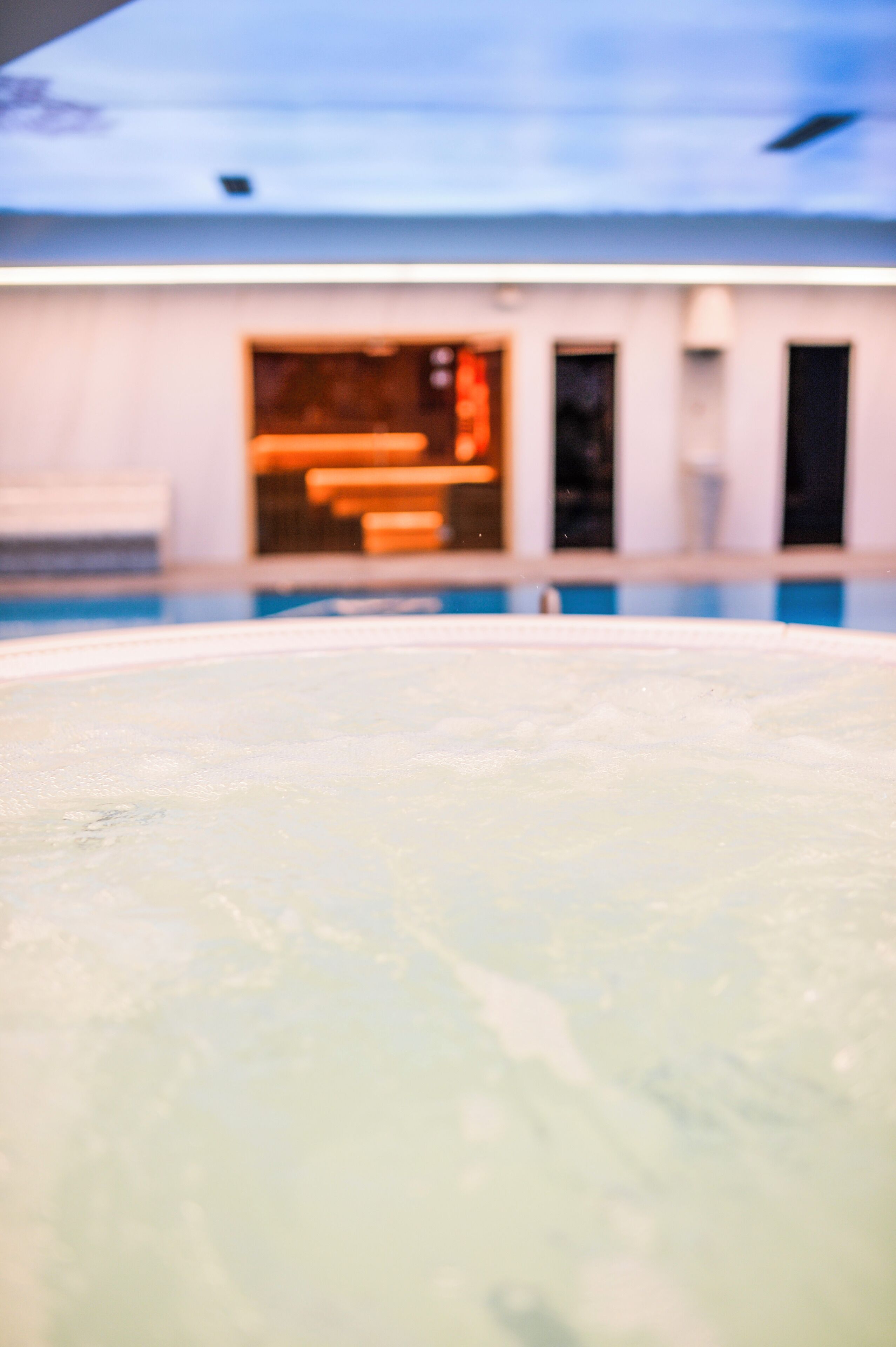 Una piscina con un fondo desenfocado de un edificio de diseño moderno y amplias ventanas.