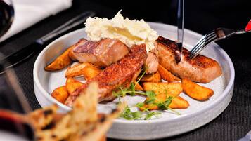 A plate of food with various meats and vegetables, a fork, and a knife.