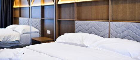Camera d'albergo dal design moderno, con un letto grande con lenzuola bianche, una testiera con motivi geometrici e una parete rivestita in legno con illuminazione a triangolo.