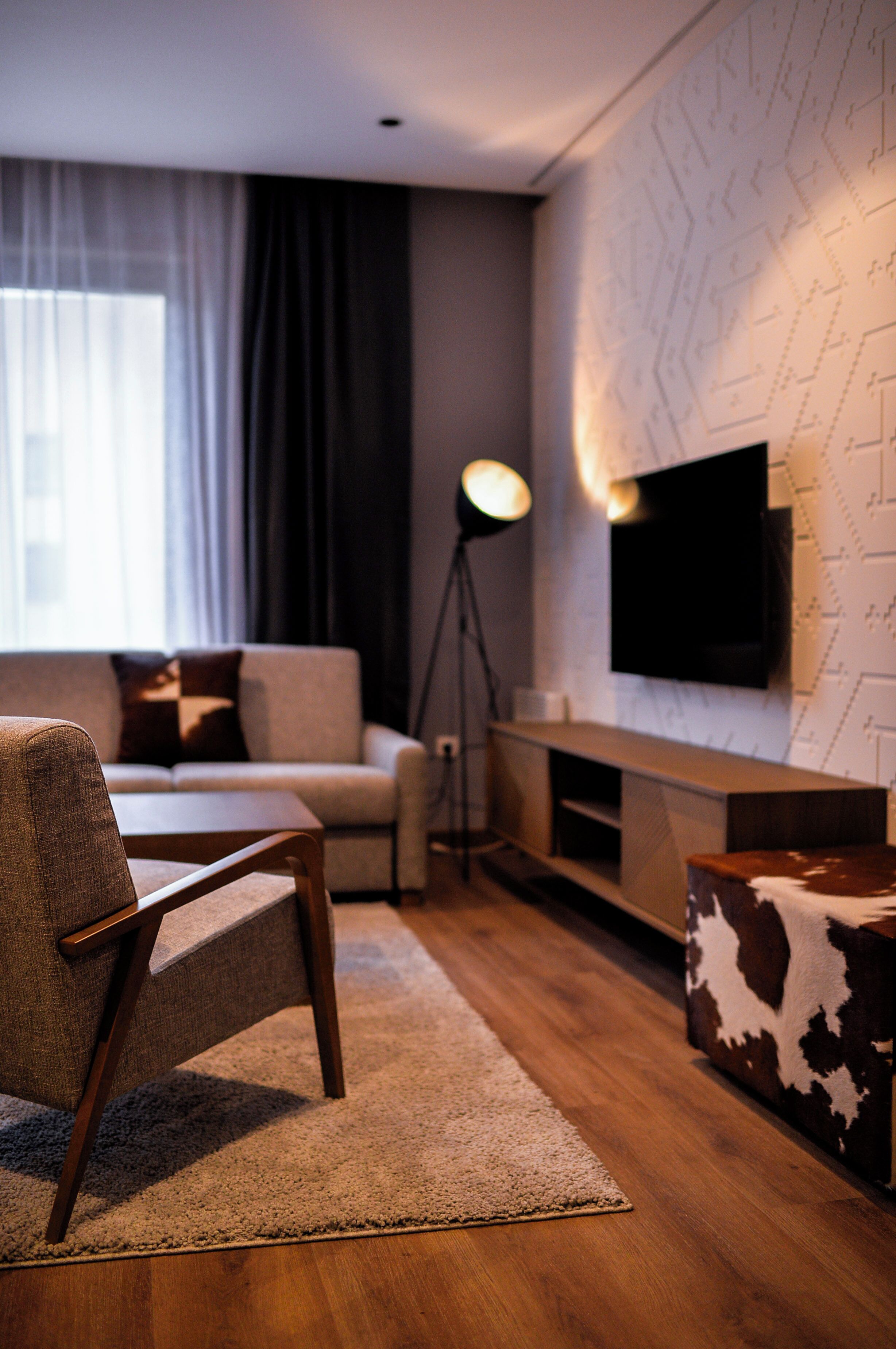 Una sala de estar moderna con un sofá, una mesa de centro, un televisor montado en la pared y una lámpara de pie.