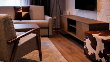 Una sala de estar moderna con un sofá, una mesa de centro, un televisor montado en la pared y una lámpara de pie.