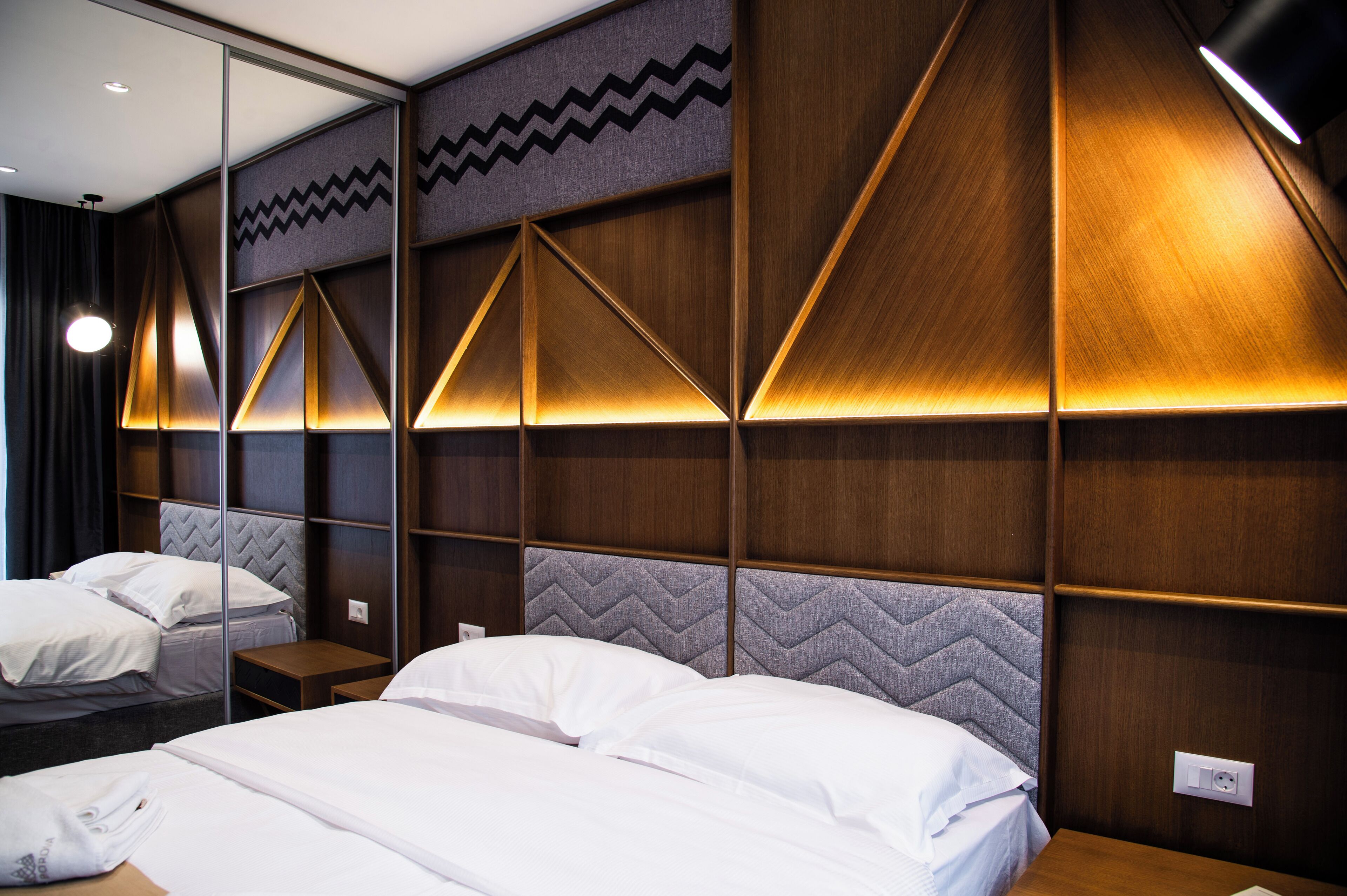 Habitación de hotel con dos camas y cabeceros de madera, además de un espejo.