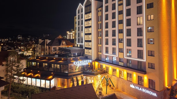Un hotel de varios pisos con un diseño moderno, que destaca un letrero con 'Evergreen Inn Bestoran' y 'Vila Borova'.