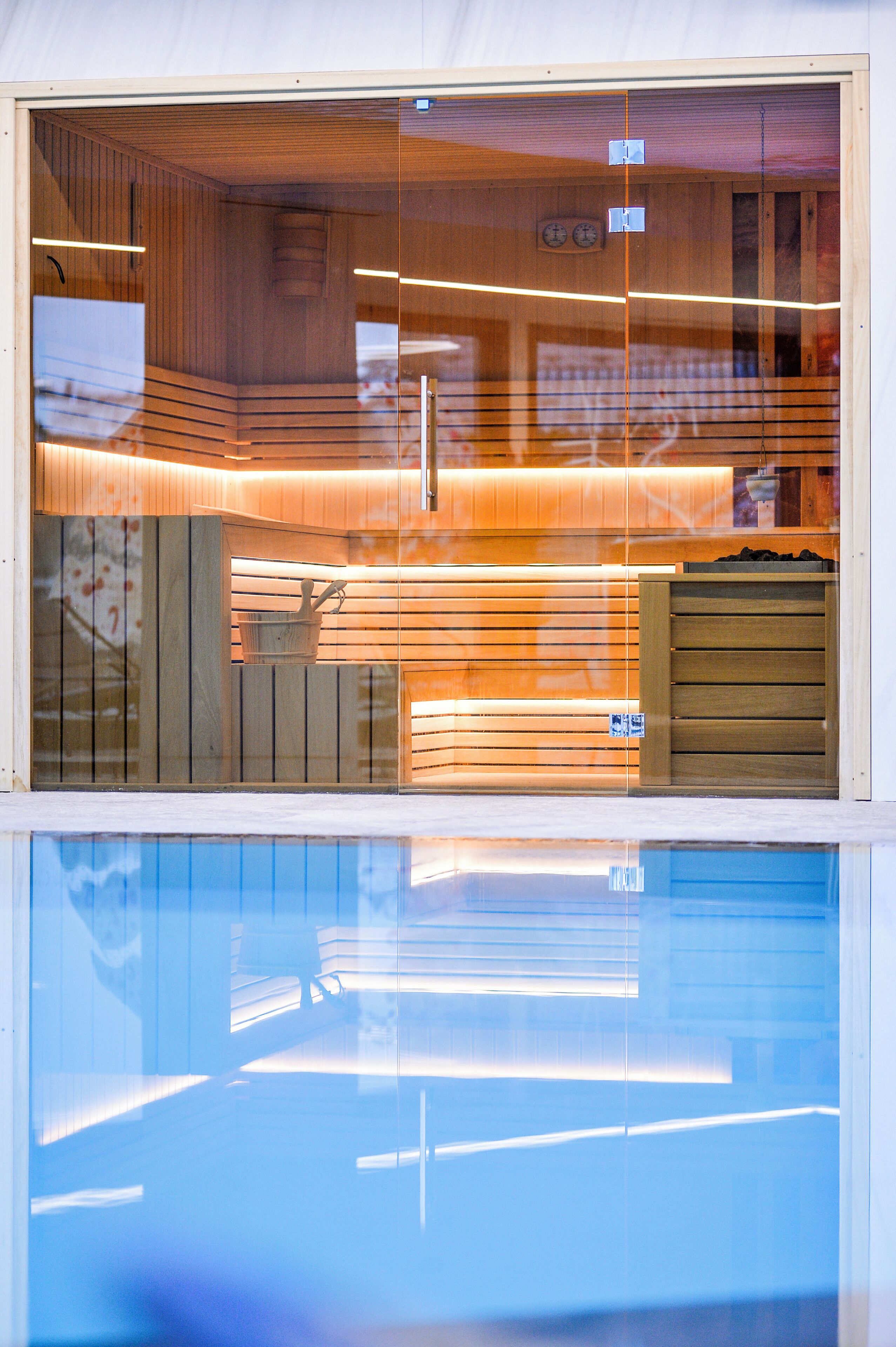Ein modernes Interieur mit Holzvertäfelung, einer sichtbaren Uhr und einem Spiegelbild im Glas.