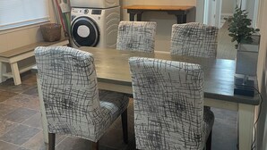 A dining area with a round table and four chairs with a black and white pattern. There is a chandelier above the table, a washing machine, and a small plant on the table. - Chic & Spacious 3-Bedroom Retreat in the Heart of Clarksville (Clarksville)