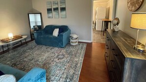 A living room with a blue sofa, a coffee table, a rug, a dresser, and a clock on the wall. - Chic & Spacious 3-Bedroom Retreat in the Heart of Clarksville (Clarksville)