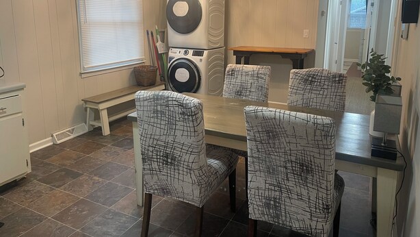 A dining area with a round table, four chairs with a black and white pattern, a ceiling light fixture, and a washing machine in the background. - Chic & Spacious 3-Bedroom Retreat in the Heart of Clarksville (Clarksville)