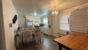 A compact kitchen with a dining area, featuring a wooden table, four chairs, and a pendant light. - Chic & Spacious 3-Bedroom Retreat in the Heart of Clarksville (Clarksville)