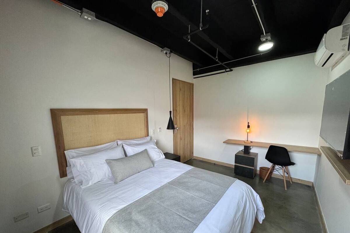 A modern hotel room with a large bed, a desk, and a chair.