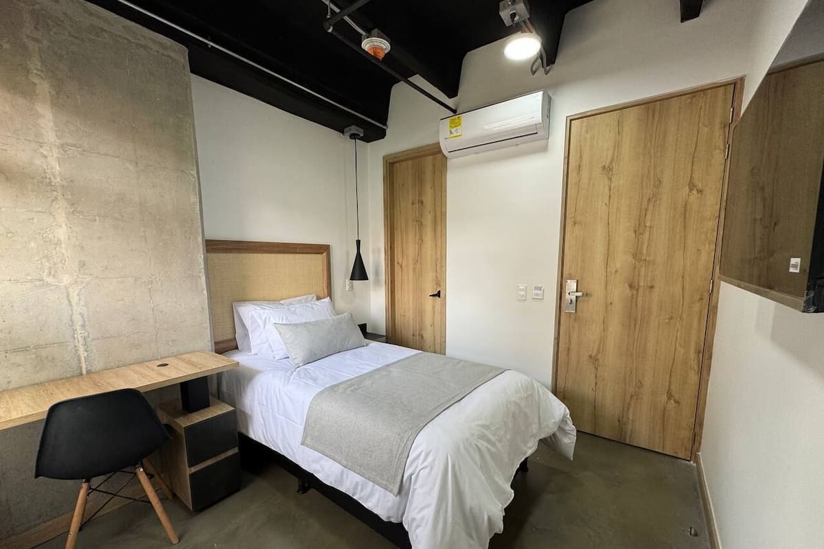 A compact bedroom with a bed, a desk, and a chair.