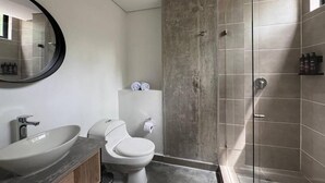 A modern bathroom with a large oval sink, a toilet, and a glass-enclosed shower. - Akela Park (Medellín)