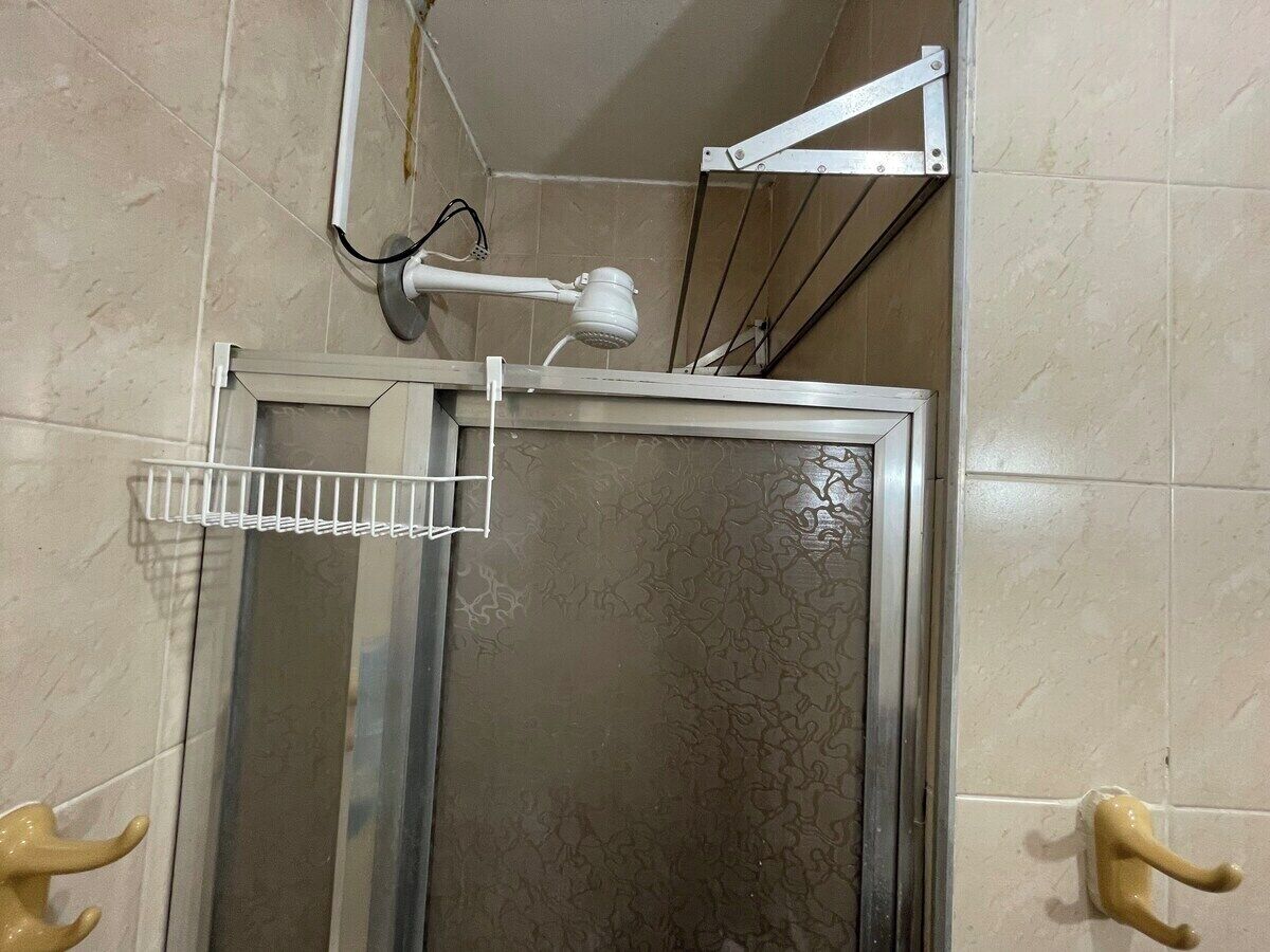 A shower area with a glass door, a metal rack, and a towel rack.