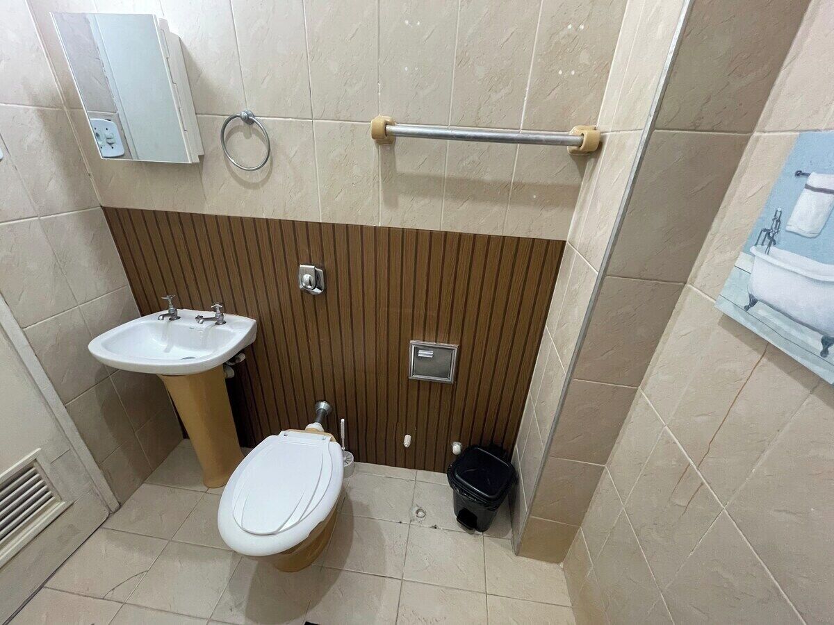 A bathroom with a toilet, sink, and a towel rack.