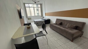 Una sala de estar moderna con un sofá, una mesa de comedor con sillas y un ventanal que proporciona luz natural.
