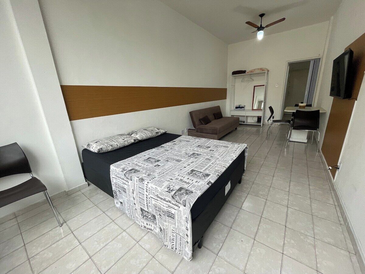 A bedroom with a bed, a chair, a desk, and a ceiling fan.