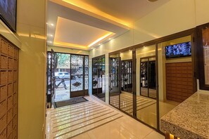 A hotel lobby with a reception desk, a television, and a view of the street outside.
