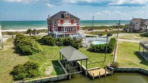 Een ruim herenhuis met twee verdiepingen, een balkon, een zwembad en een steiger die uitsteekt in het water.