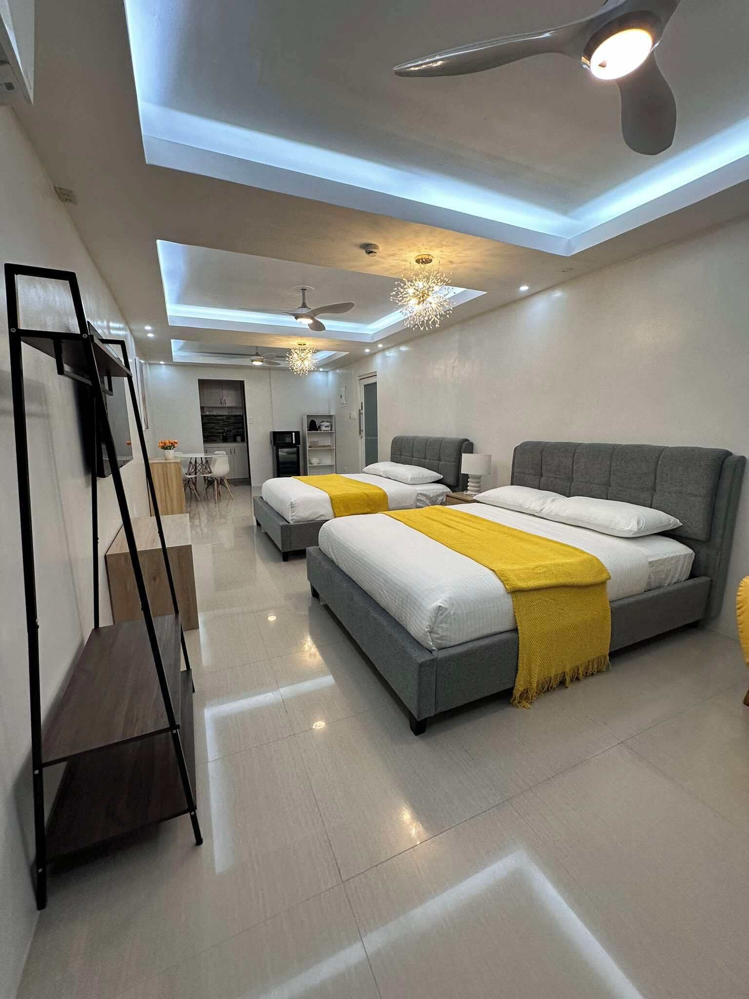 A modern bedroom with two beds, a ceiling fan, and a skylight.