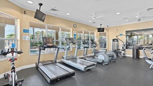 Een fitnessruimte met loopbanden, elliptische trainers en een hometrainer.