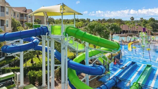 Een waterpark met meerdere glijbanen en zwembaden, omringd door groen en gebouwen.