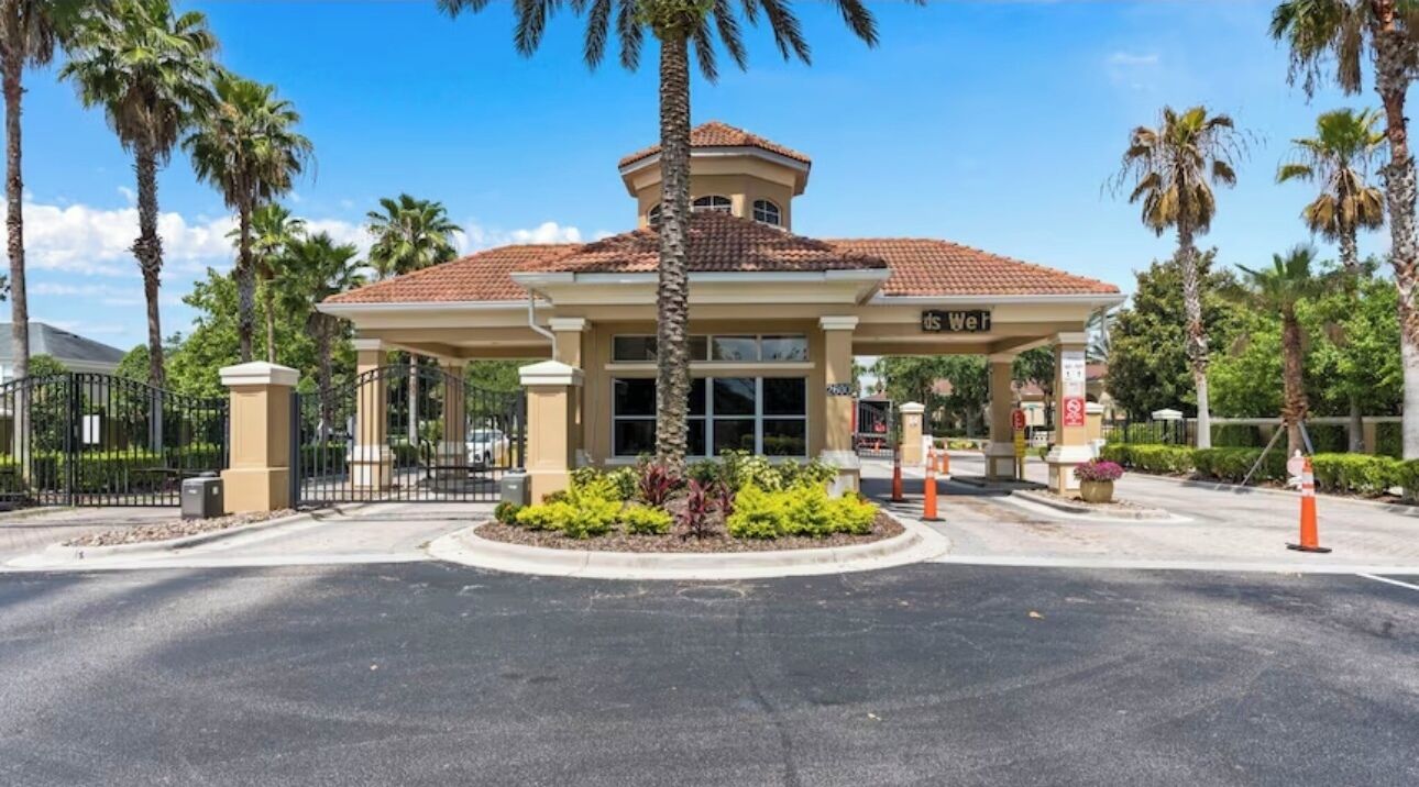 Ein Hotel mit Eingangsbereich, überdachter Terrasse, Palmen und befestigter Auffahrt.