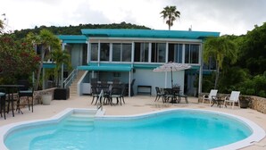 Ein modernes Haus mit Swimmingpool, Außenbereich mit Sitzgelegenheiten und einer Treppe zum Obergeschoss.