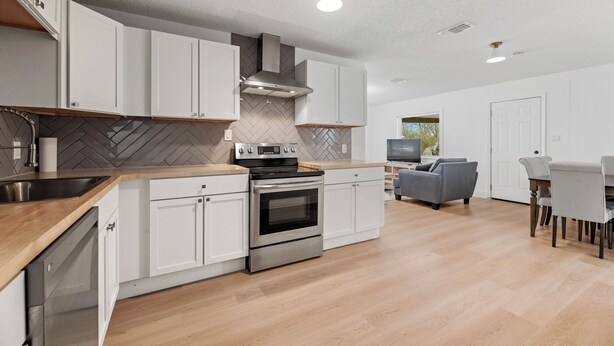 Eine moderne Küche mit weißen Schränken, Edelstahlgeräten und einer backsplash in Fischgrätmusterung.