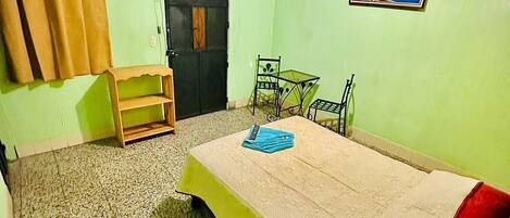 Una habitación con una cama, un escritorio, una silla, un televisor en la pared y un cuadro.