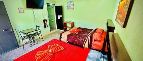 Une chambre d’hôtel avec un lit, un bureau, une chaise, une télévision et une porte.