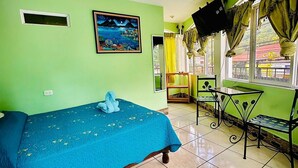 A room with a bed, a table, a chair, a painting, and a window with curtains. - Hotel Emiss Panajachel  (Panajachel)