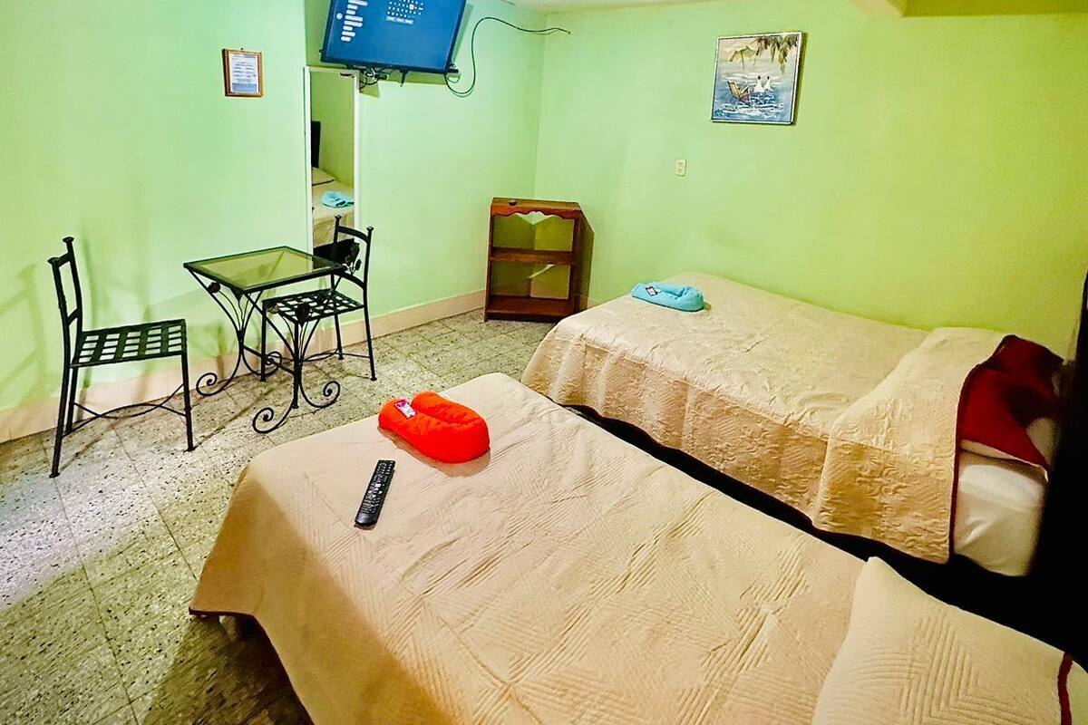 A small, single-room accommodation with a bed, a desk, a chair, and a television.