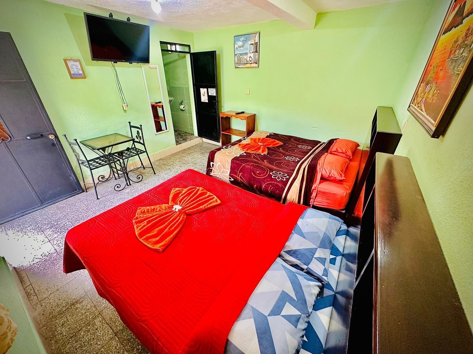 Una habitación con dos camas, un escritorio, una silla y una televisión.