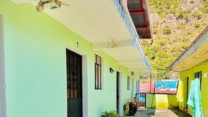 A building with a covered corridor, a door with a number, and a small garden area with plants. - Hotel Emiss Panajachel  (Panajachel)