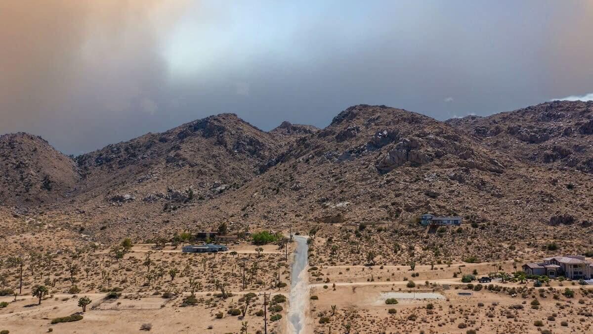 Un paysage désertique avec des montagnes en arrière-plan et un petit bâtiment au premier plan.